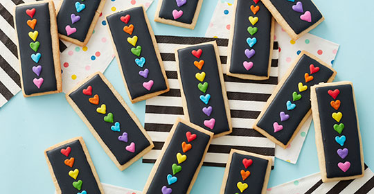 Square cookies with black icing and multi-colored hearts 